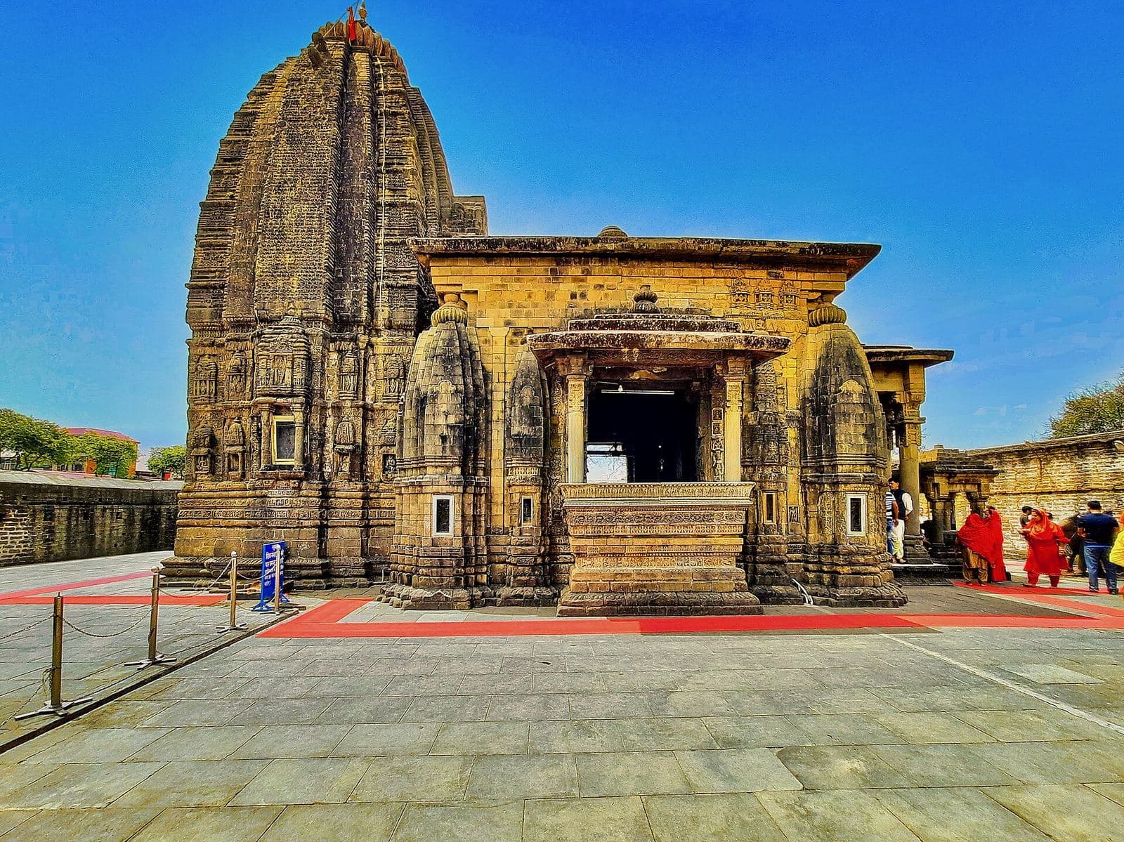 The stone Baijnath temple in Kangra, with its tall carved spire, under a blue sky.