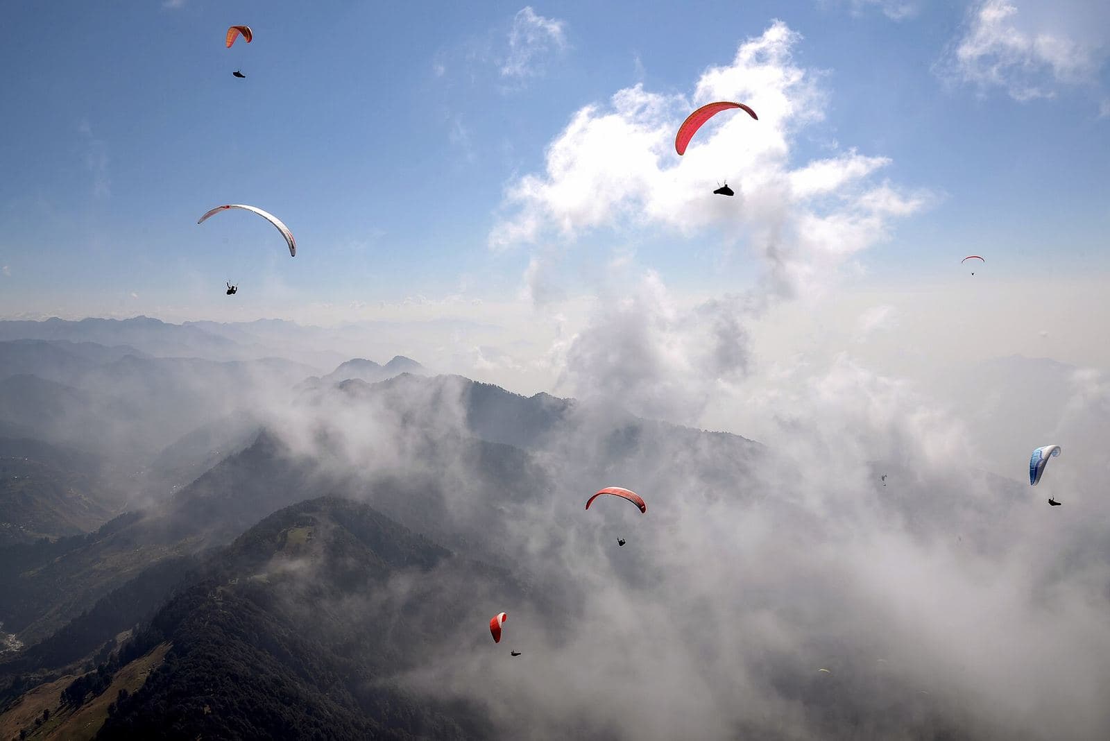 Paragliders in the sky above the clouds and hills at Bir Billing.