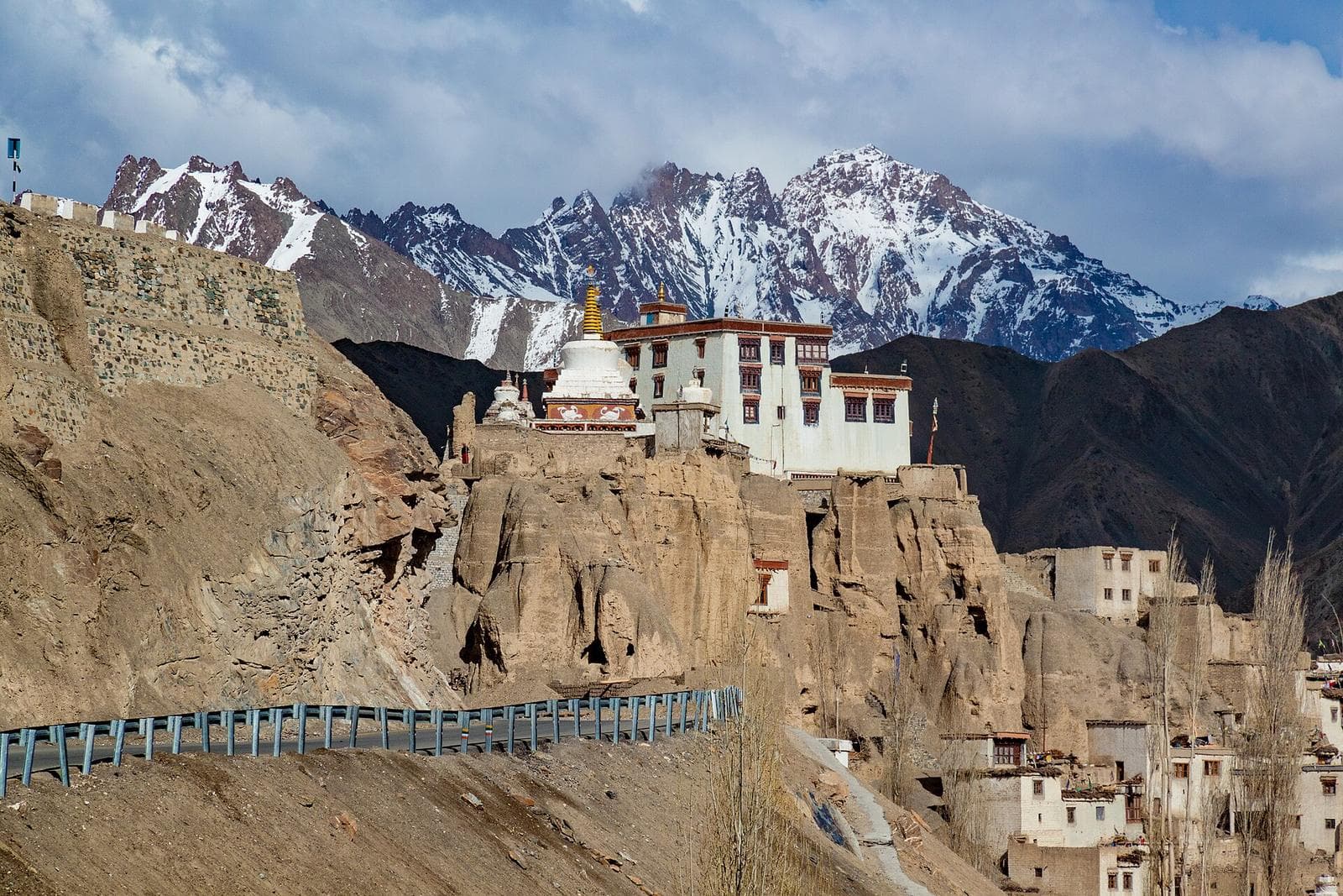 Lamayuru Monastery on its eroded cliff, with snow-streaked peaks behind.