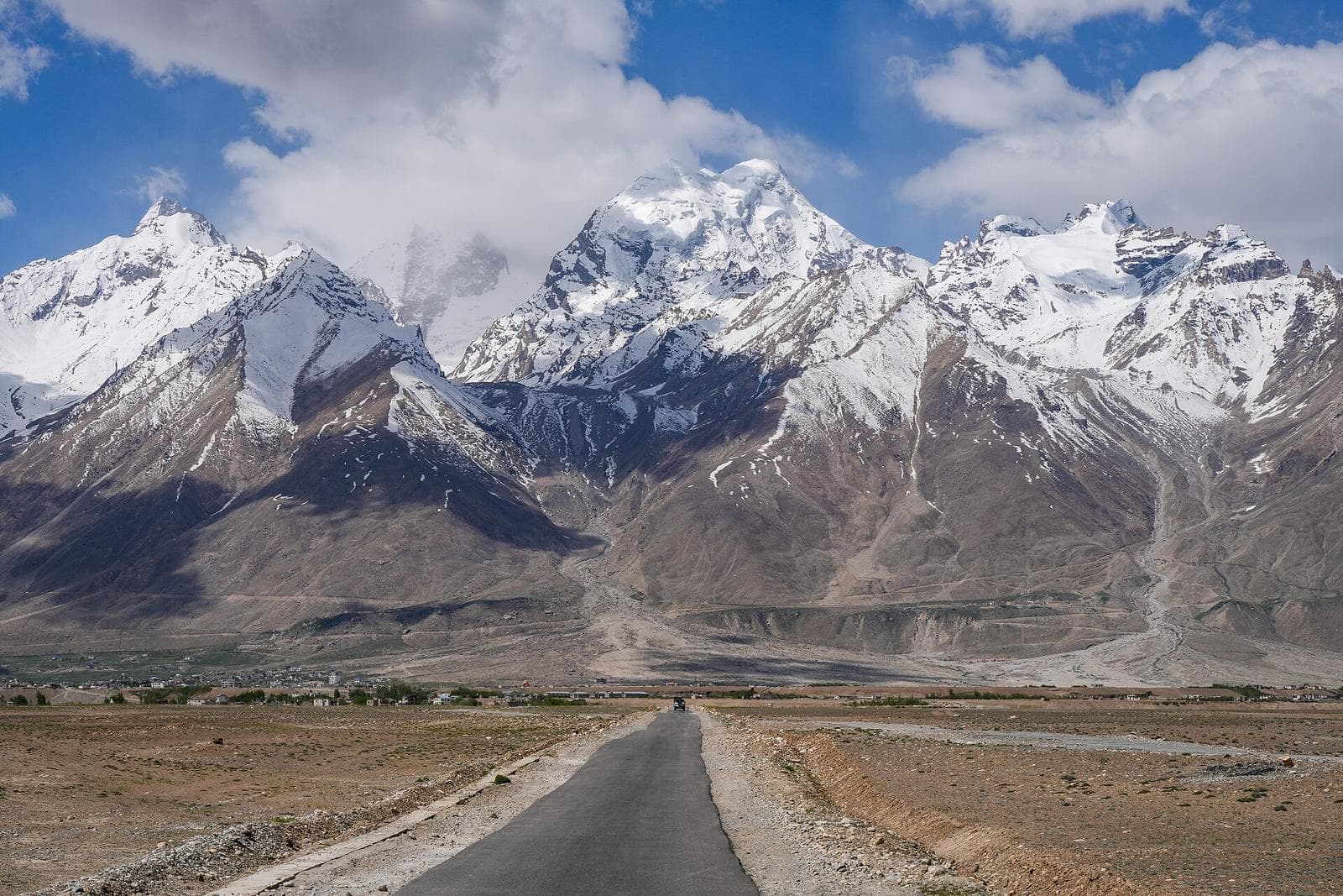 A straight road across the Padum plain toward the snow-capped Zanskar range.