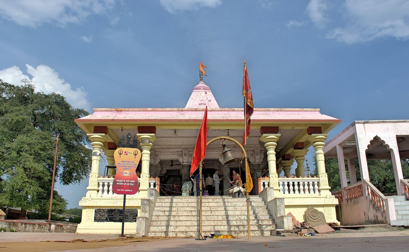 The Kal Bhairav temple in Ujjain, a white and pink hall with saffron flags flying above its steps.