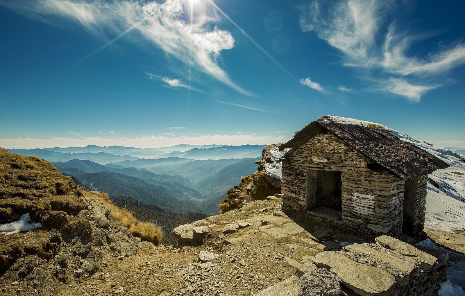 The small stone temple on Chandrashila peak, with ridges fading to the horizon below.