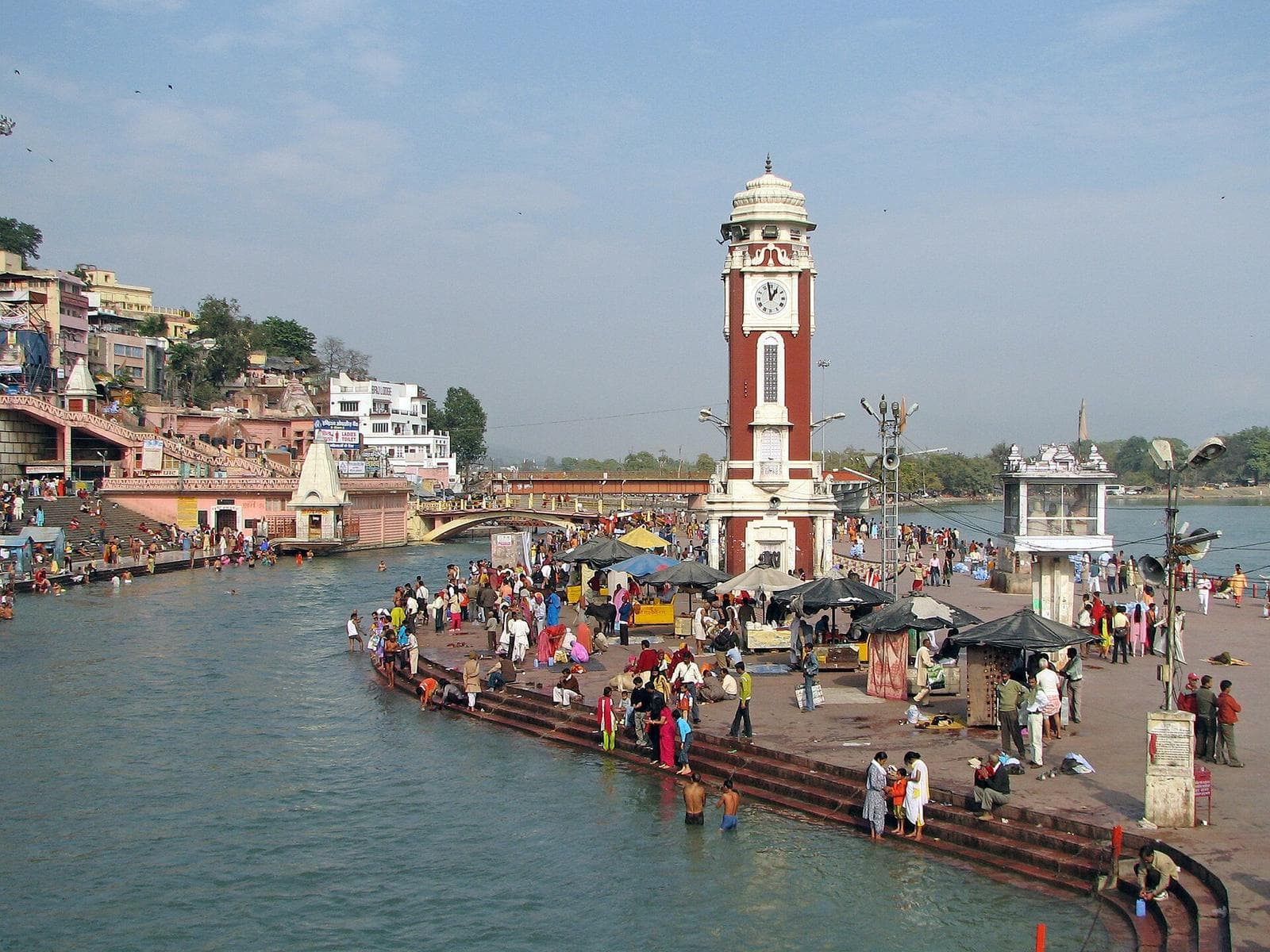 The clock tower at Har Ki Pauri in Haridwar, with pilgrims on the ghats beside the Ganga.